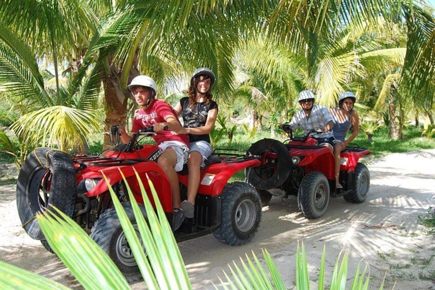 Trois personnes sur des quad rouges, dans un décor tropical avec des palmiers. 4