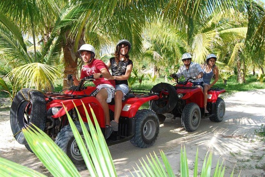 Trois personnes conduisent des quads rouges sur un chemin de terre, entourés de palmiers. 5