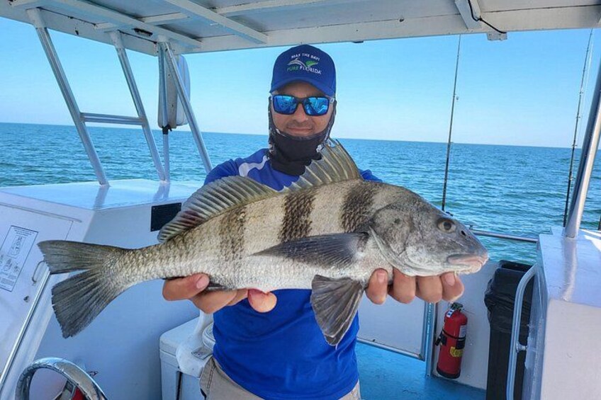 A person holding a fish on a boat with the ocean in the background. 4