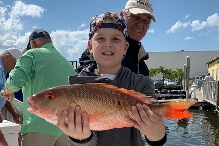 A person holding a fish, a dock, and a building in the background. 3