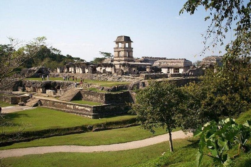 Ruinas antiguas con una estructura piramidal destacada, una amplia plaza abierta y un área verde bien cuidada. 2