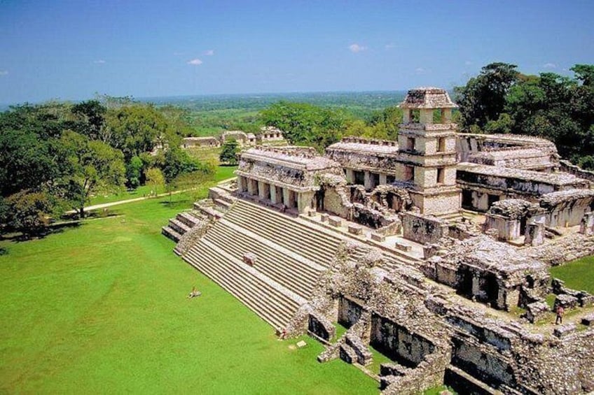 An ancient Mayan pyramid complex with terraced structures and a large open plaza. 1
