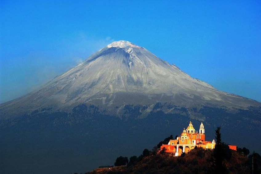 Una montaña nevada, una iglesia y un cielo azul despejado. 1