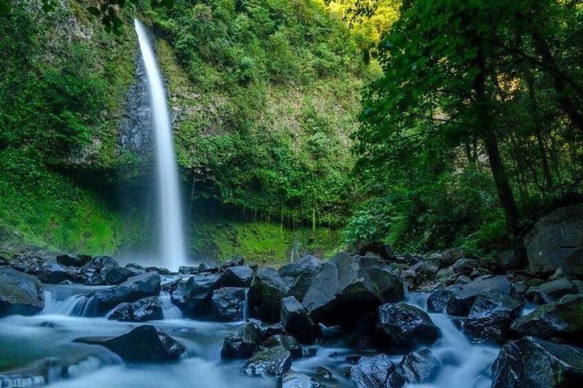 Een waterval omringd door rotsen en weelderige begroeiing. 3