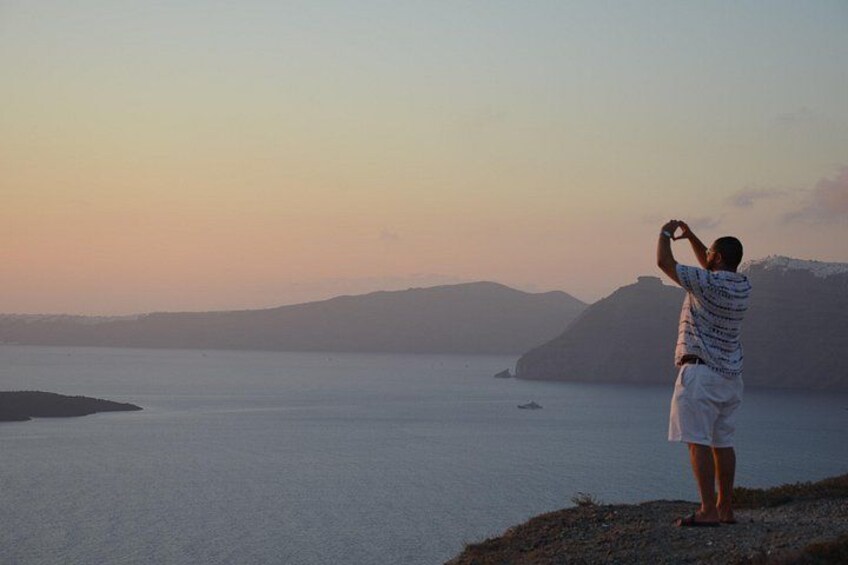 Une personne prend une photo d’une mer calme, avec des montagnes lointaines, au coucher du soleil. 5