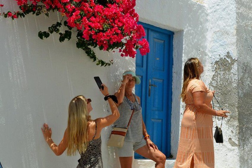 A white building with a blue door, pink flowers, and people taking photos. 5