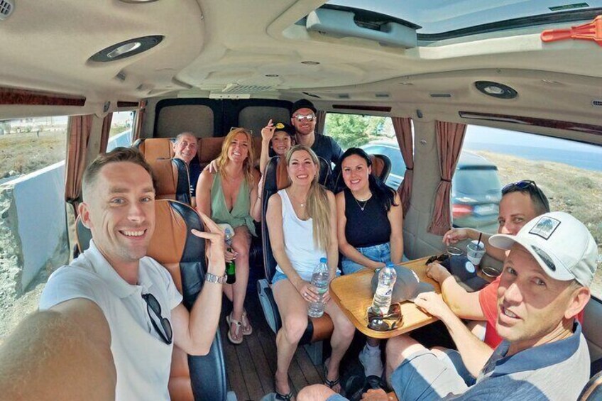 A group of people inside a vehicle with a table and drinks. 5
