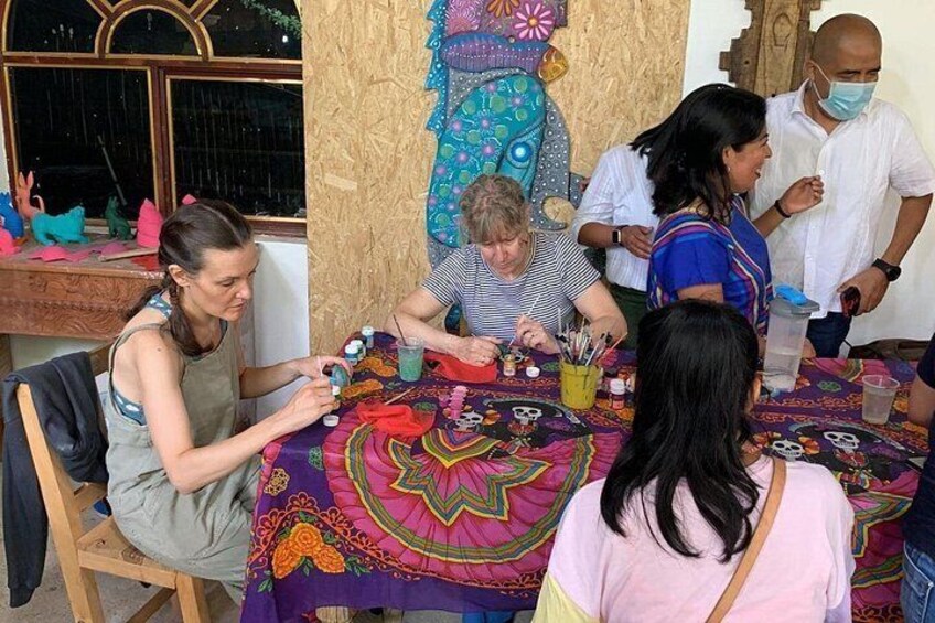 A group of people engaged in a craft activity at a table with colorful fabrics and tools. 1