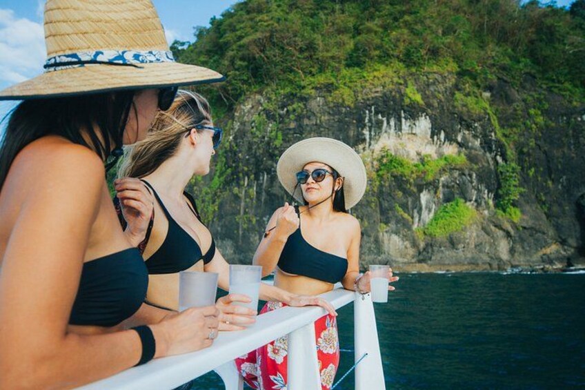 Dos personas en un bote, una con sombrero de paja y la otra con gafas de sol, con un acantilado rocoso y el océano al fondo. 4