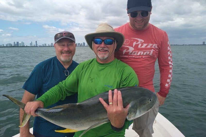 Three people on a boat holding a large fish. 1