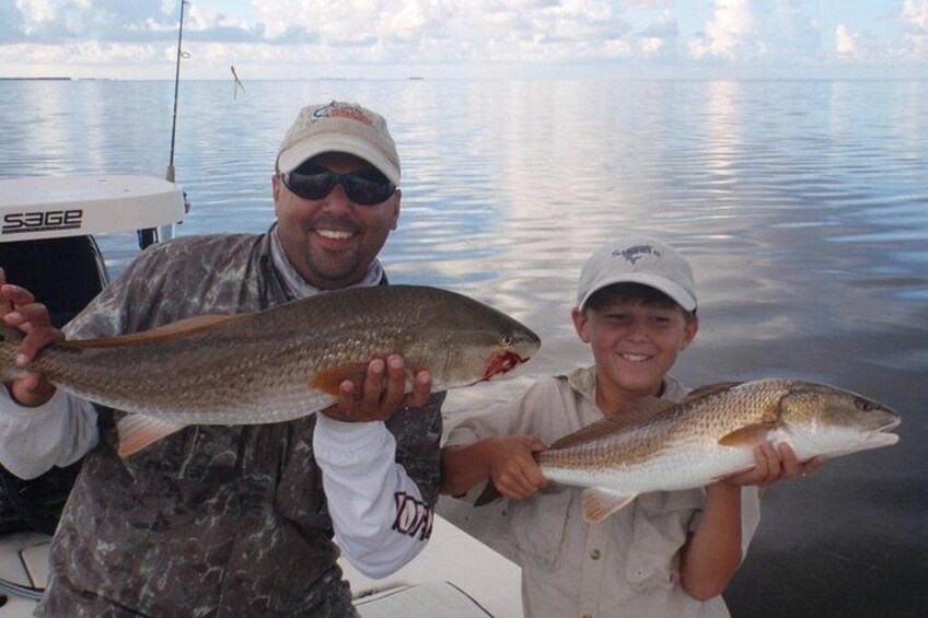 Two people holding fish on a boat. 3