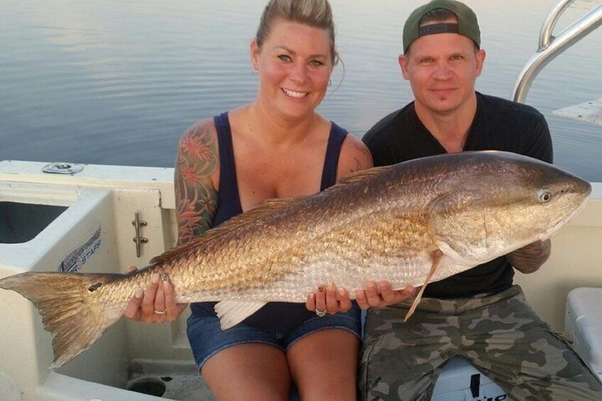 Two people holding a large fish on a boat. 1