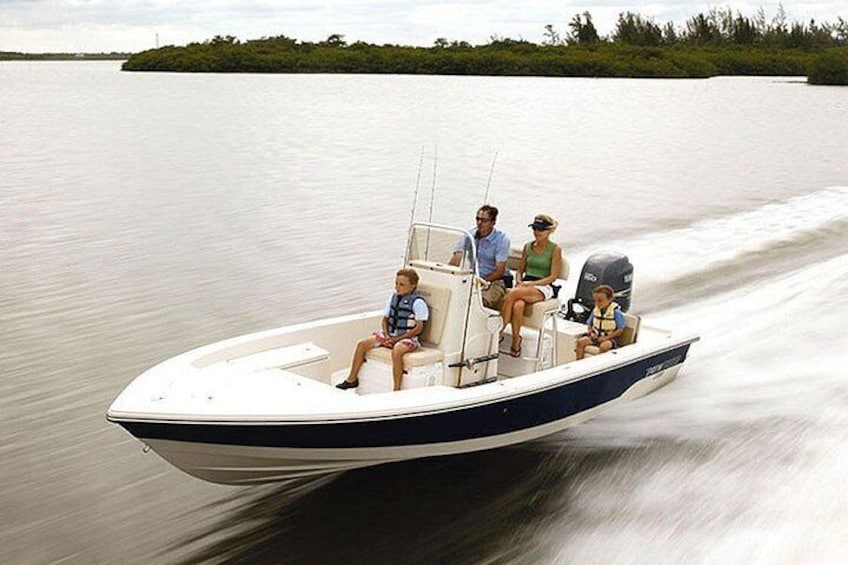 Een gezin op een speedboot dat over stil water vaart, met een bebost eiland op de achtergrond. 4