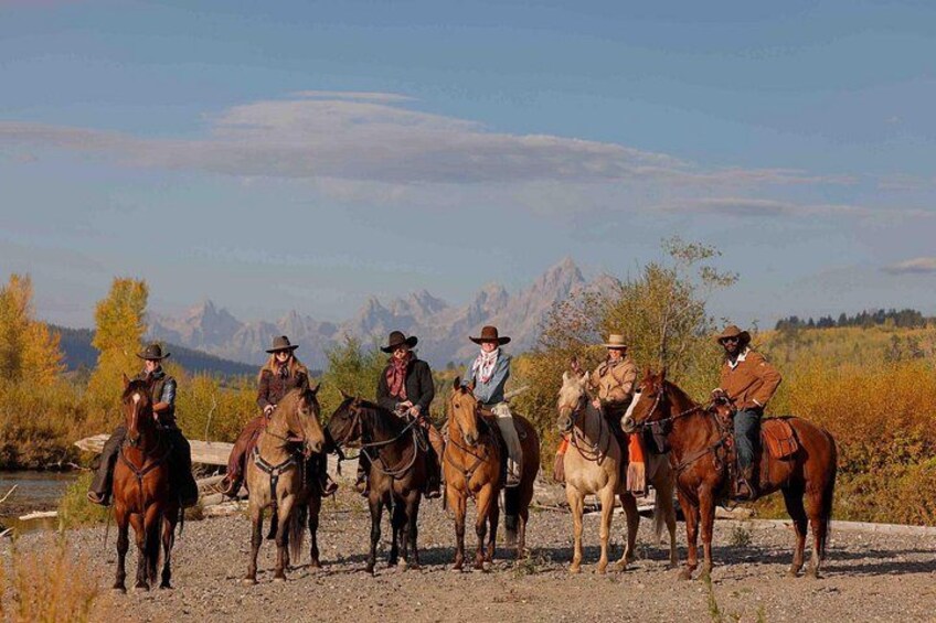 A group of people on horseback in a natural setting with mountains in the background. 2