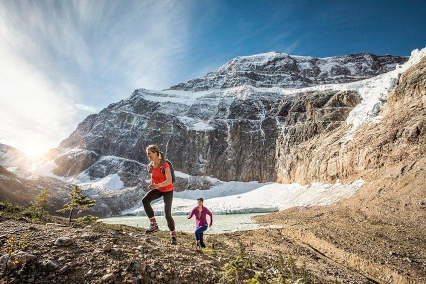 A mountainous landscape with a glacier, a person in a red top, and a child in a pink top. 1