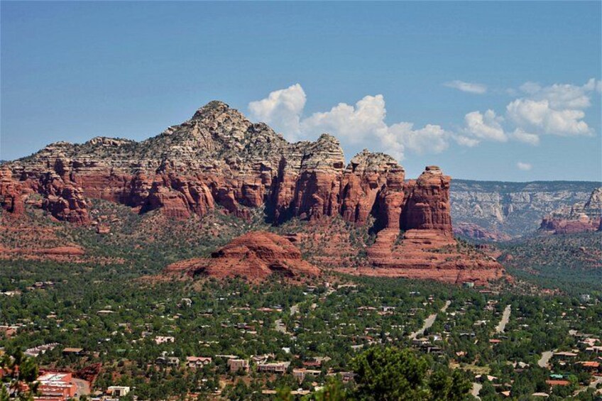 A red rock formation with a town in the foreground. 3
