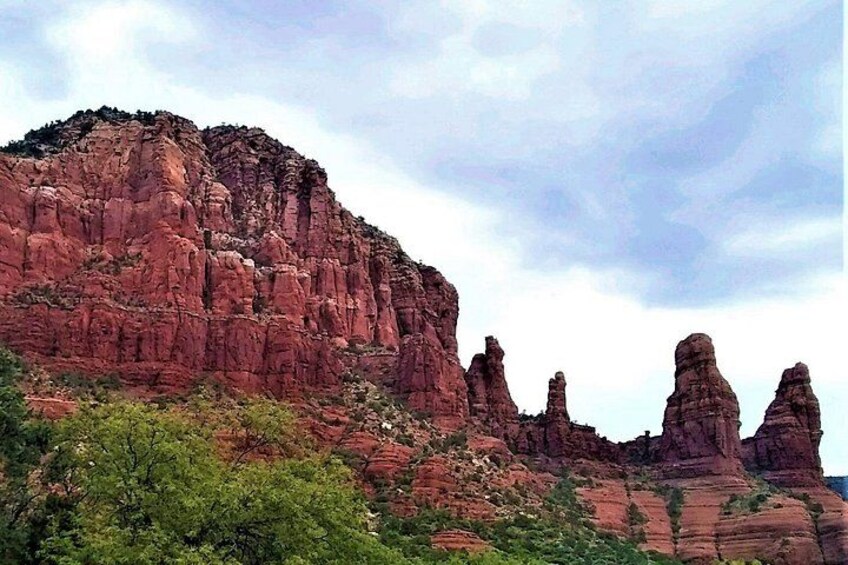 A red rock formation with a prominent peak and several smaller peaks in the foreground. 1