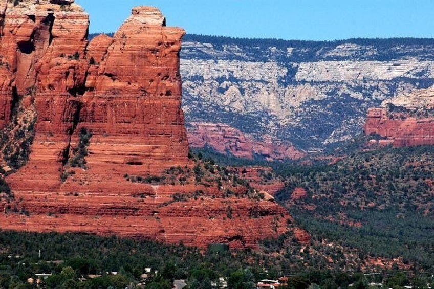 A red rock formation with a forested valley and distant mountains. 2