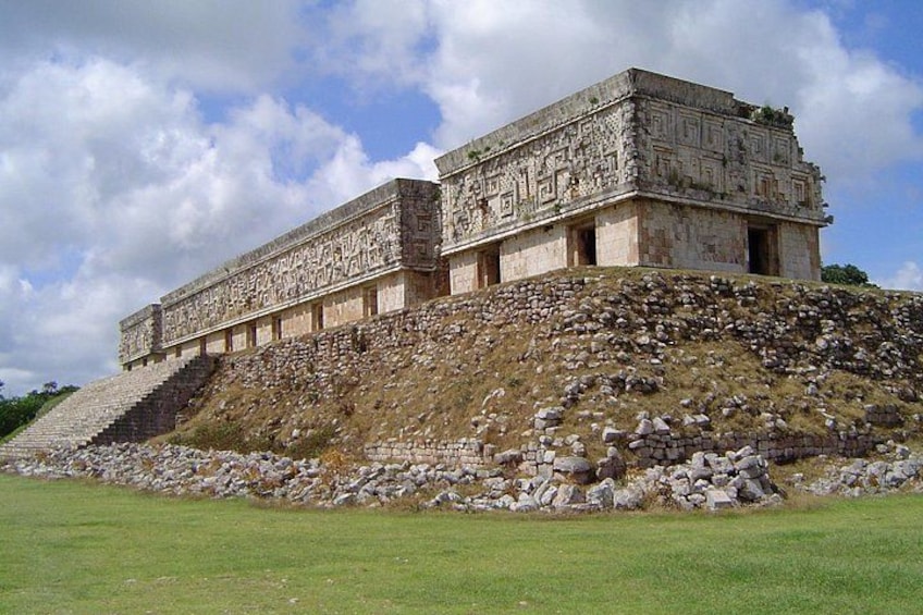 Una gran estructura de piedra antigua con intrincados grabados, ubicada en una colina cubierta de pasto bajo un cielo despejado. 2