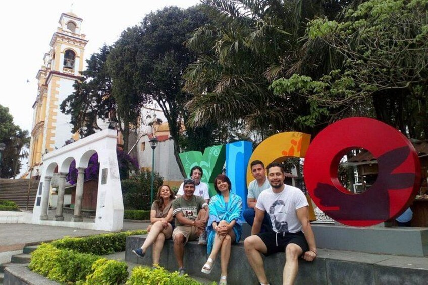 A group of people sitting on a ledge with a historic building and colorful sculptures in the background. 3