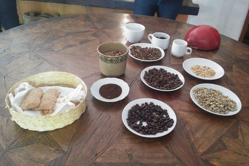 A wooden table with various bowls of beans, a basket of bread, and a red mug. 1
