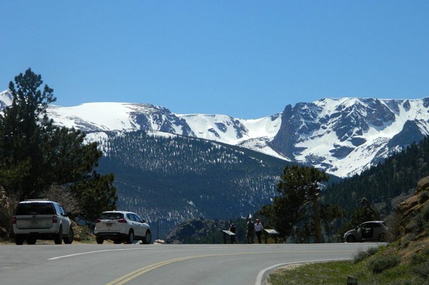 A road with cars, a mountain range, and trees. 2