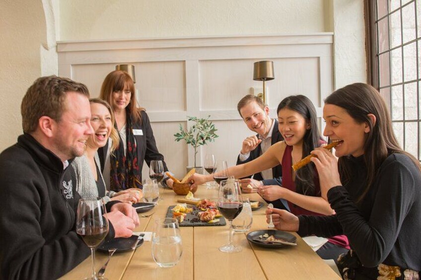 Un grupo de personas sentadas alrededor de una mesa, con copas de vino y platos de comida. 1