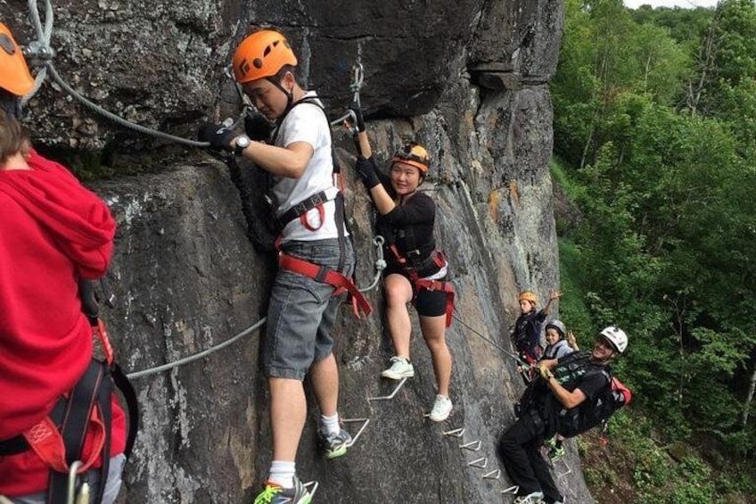 People engaged in rock climbing on a large rock face with safety harnesses and ropes. 2