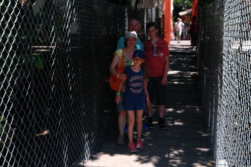 Una cerca de malla metálica, una persona con camisa azul y un niño con camisa azul que lleva la palabra 'BEST'. 3