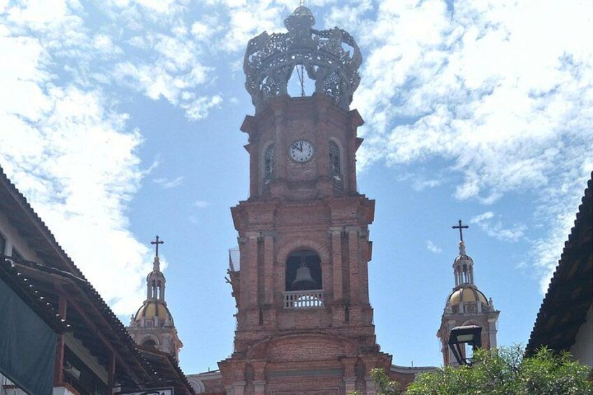 Una iglesia con una imponente torre del reloj, una torre de campanas y una cúpula. 2