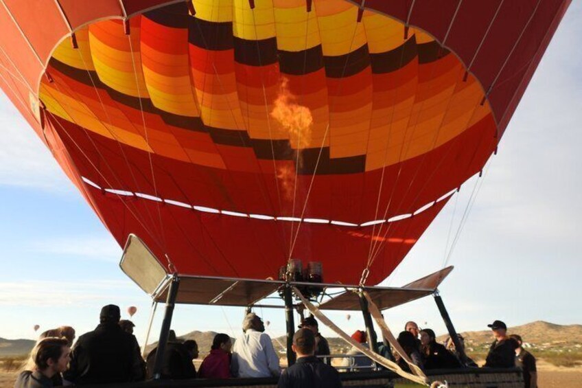 A hot air balloon with passengers, over a desert landscape. 2