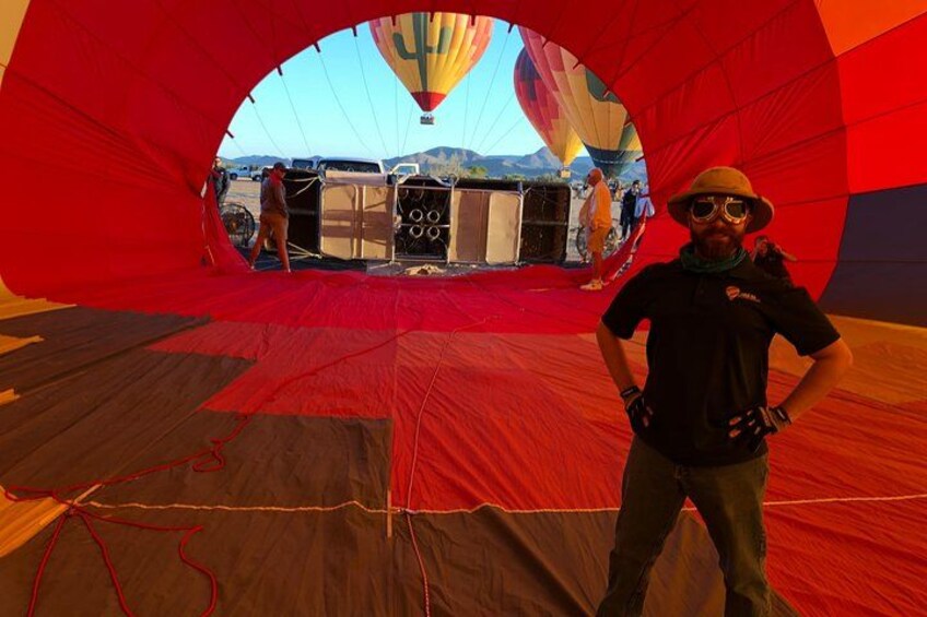 A person standing inside a large, colorful hot air balloon with a stage area visible through the opening. 2