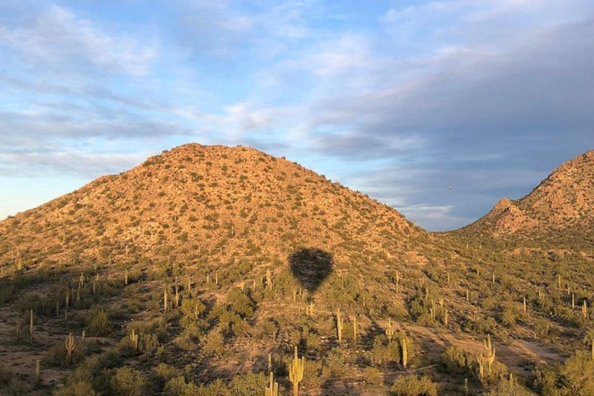 A desert landscape with two hills, sparse vegetation, and a clear sky. 4