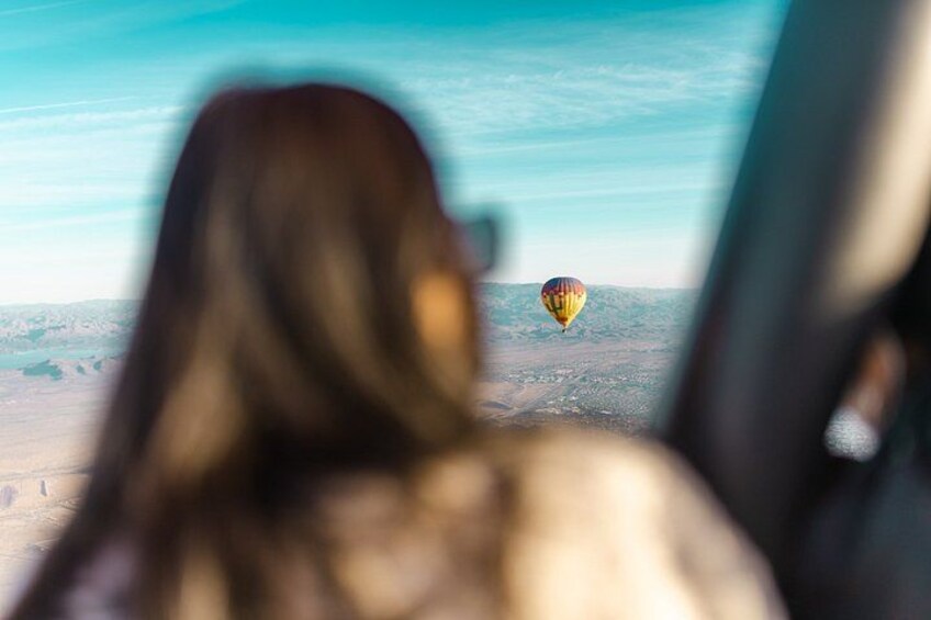 A person looking out of a window at a hot air balloon in the distance. 5