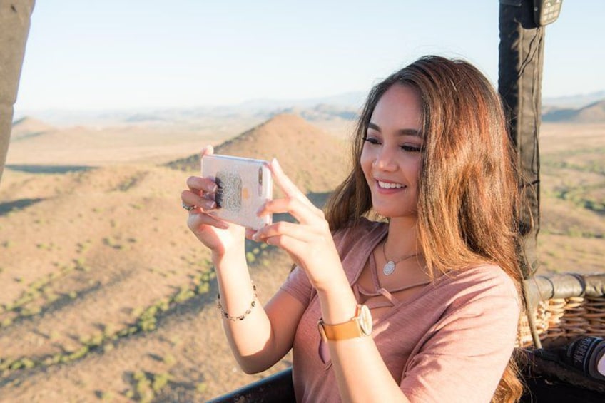 A person holding a smartphone, taking a photo of a desert landscape. 5