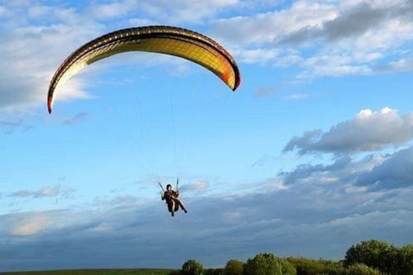 A person paragliding with a parachute in a clear sky. 1