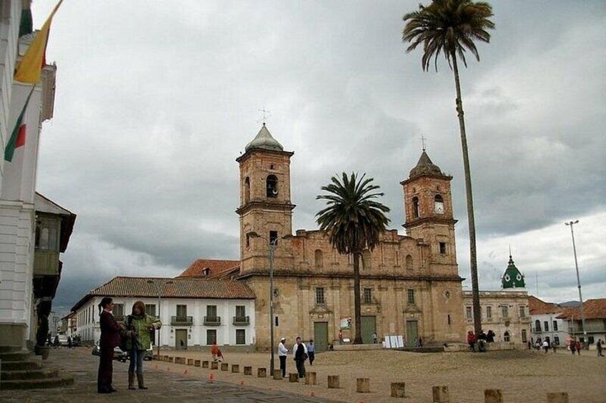 A historic building with two towers, palm trees, and a cloudy sky. 2