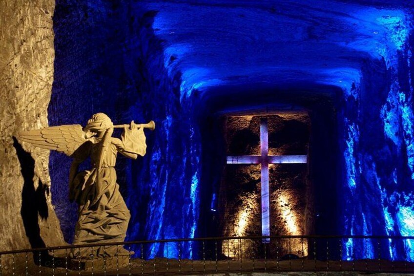 A statue of an angel with a cross in a cave. 3
