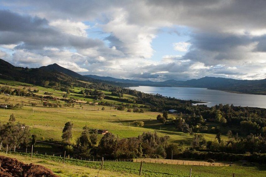 A valley with a lake, rolling hills, and a fence line. 1