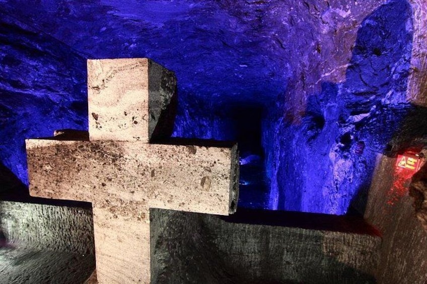 A large stone cross in a cave with a blue-lit background. 4