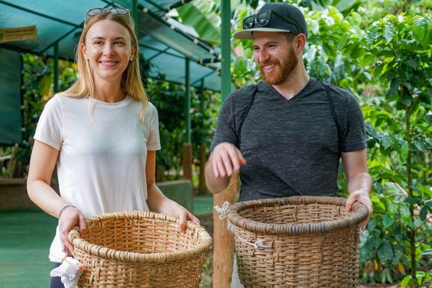 Twee personen houden manden vast in een kas met planten op de achtergrond. 3