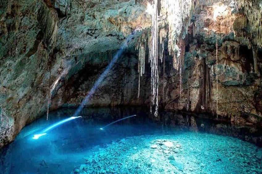 A cave with stalactites, a pool of water, and a beam of light. 5