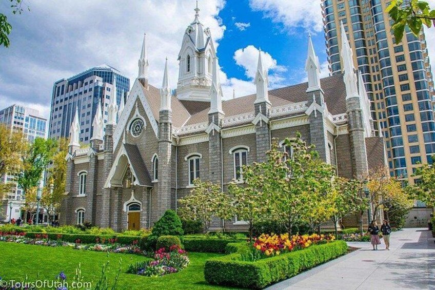Una chiesa storica con guglie appuntite e una torre dell'orologio, circondata da giardini curati e edifici moderni. 4