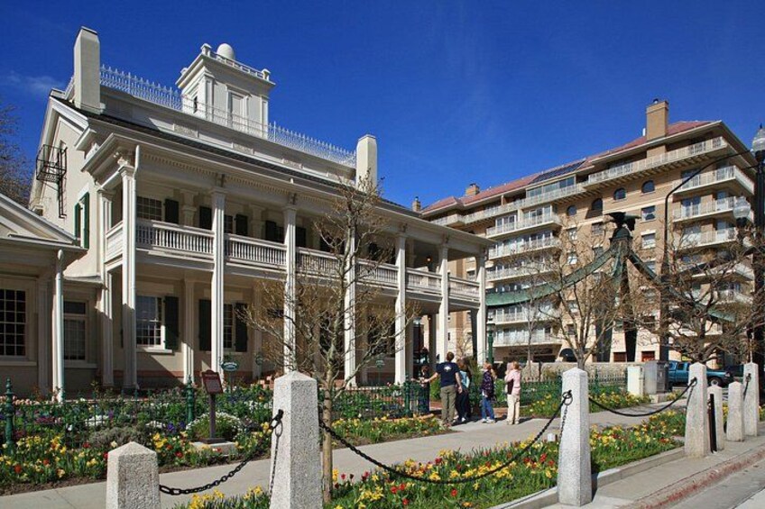 Un edificio storico con colonne, un giardino fiorito e una recinzione. 2