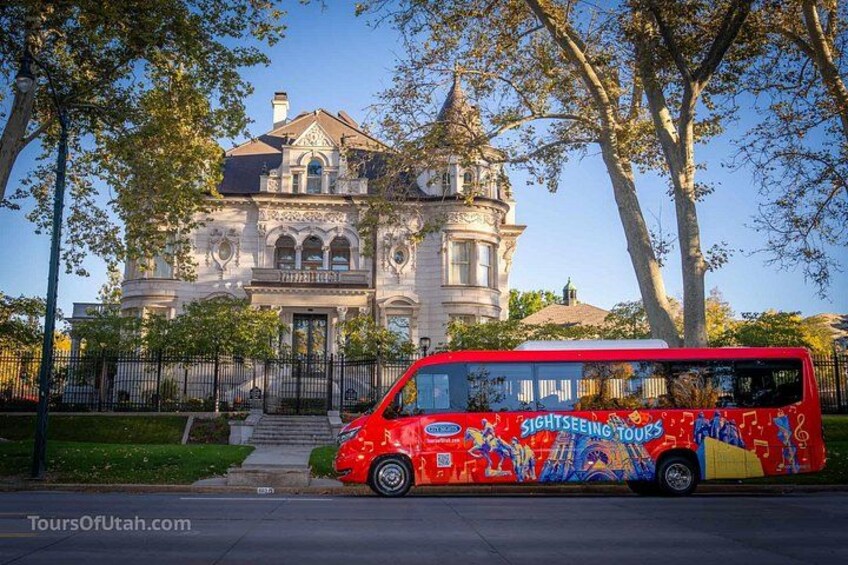 A red bus with 'Sightseeing Tours' on its side parked in front of a large, ornate building with a turret. 2