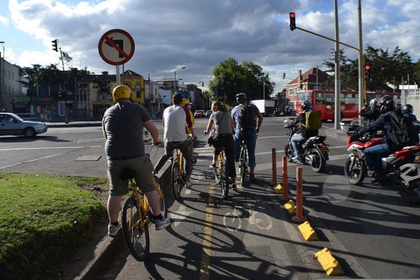 A group of cyclists waiting at a traffic light on a city street. 4