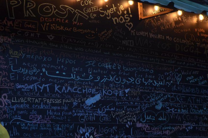 A wall covered with various writings and drawings, including names and messages. 2