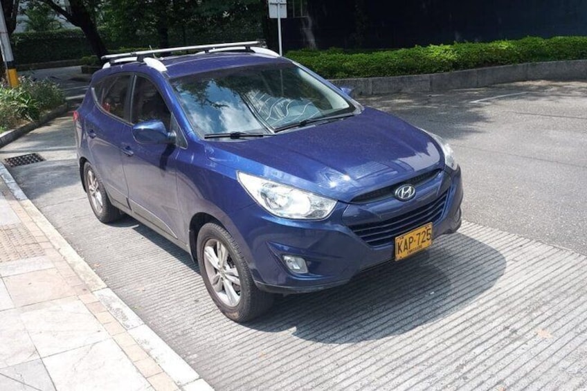 A blue Hyundai SUV parked on a city street. 4