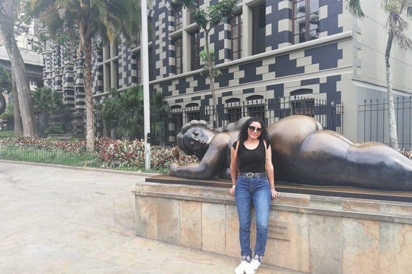 A person standing in front of a sculpture with a geometric pattern building in the background. 3