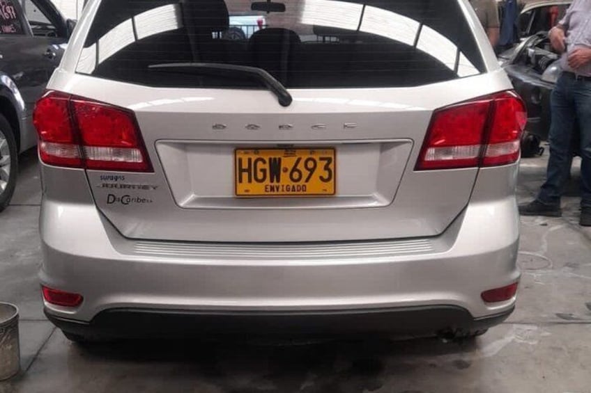 A silver car with a yellow license plate in a parking lot. 4